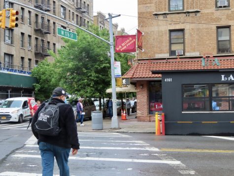 a pedestrian crossing Broadway at 176th street, walking toward a grocery store named La Rosa