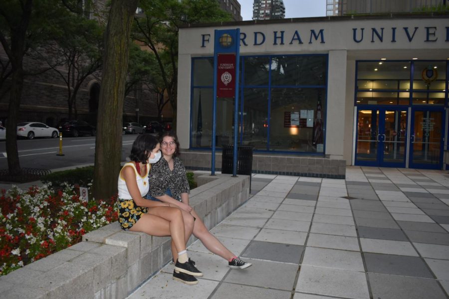 two students sitting at the FCLC plaza, one wearing a mask and the other without a mask