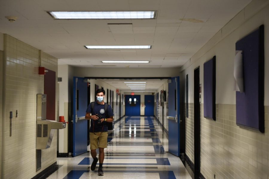 student wearing masks walks in a hallway in the Leon Lowenstein Center