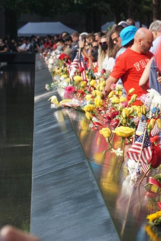 flowers and flags put in a tribute to victims of 9/11 at a memorial pool