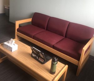 a couch and a laptop on a coffee table in a room designated for quarantine after students tested positive for COVID-19