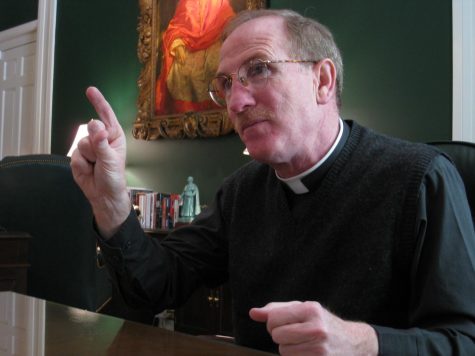 Rev McShane sits in an office and points while speaking