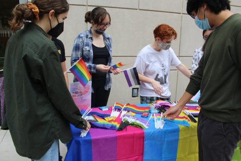 members of the lgbtq+ history month committee give out flags for the office of multicultural affairs event