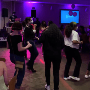 at mucho gusto hosted by SOL at fordham, students dancing with pink and purple lighting