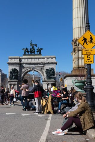 a nyc band plays live music at the entrance to prospect park with view of the gate and a sign and many people