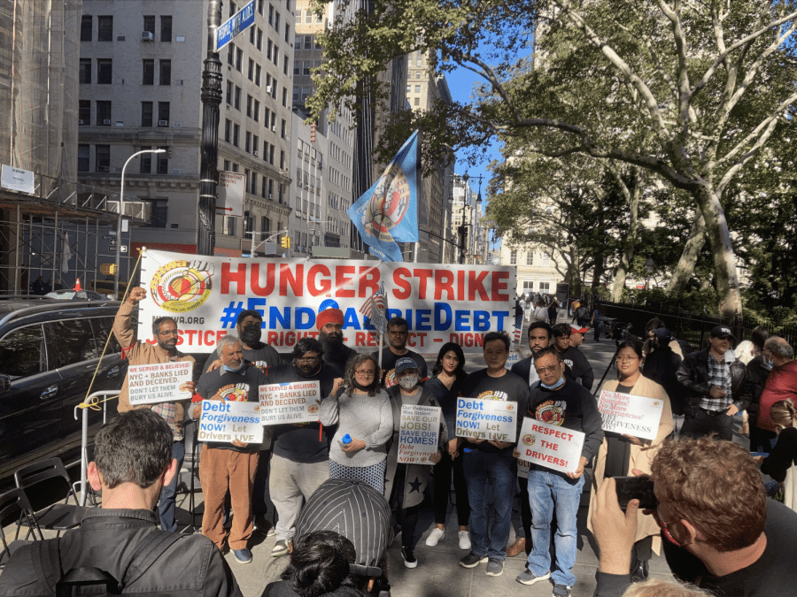 Taxi Workers Alliance members surrounding a banner at a gathering