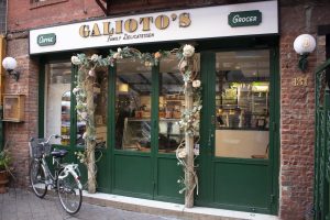 The Galioto storefront is adorned with flowers and vines. A bicycle sits in front of the window.