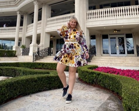 salvucci stands in a courtyard wearing a patterned printed dress with black sneakers