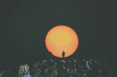 sun image shines behind singer