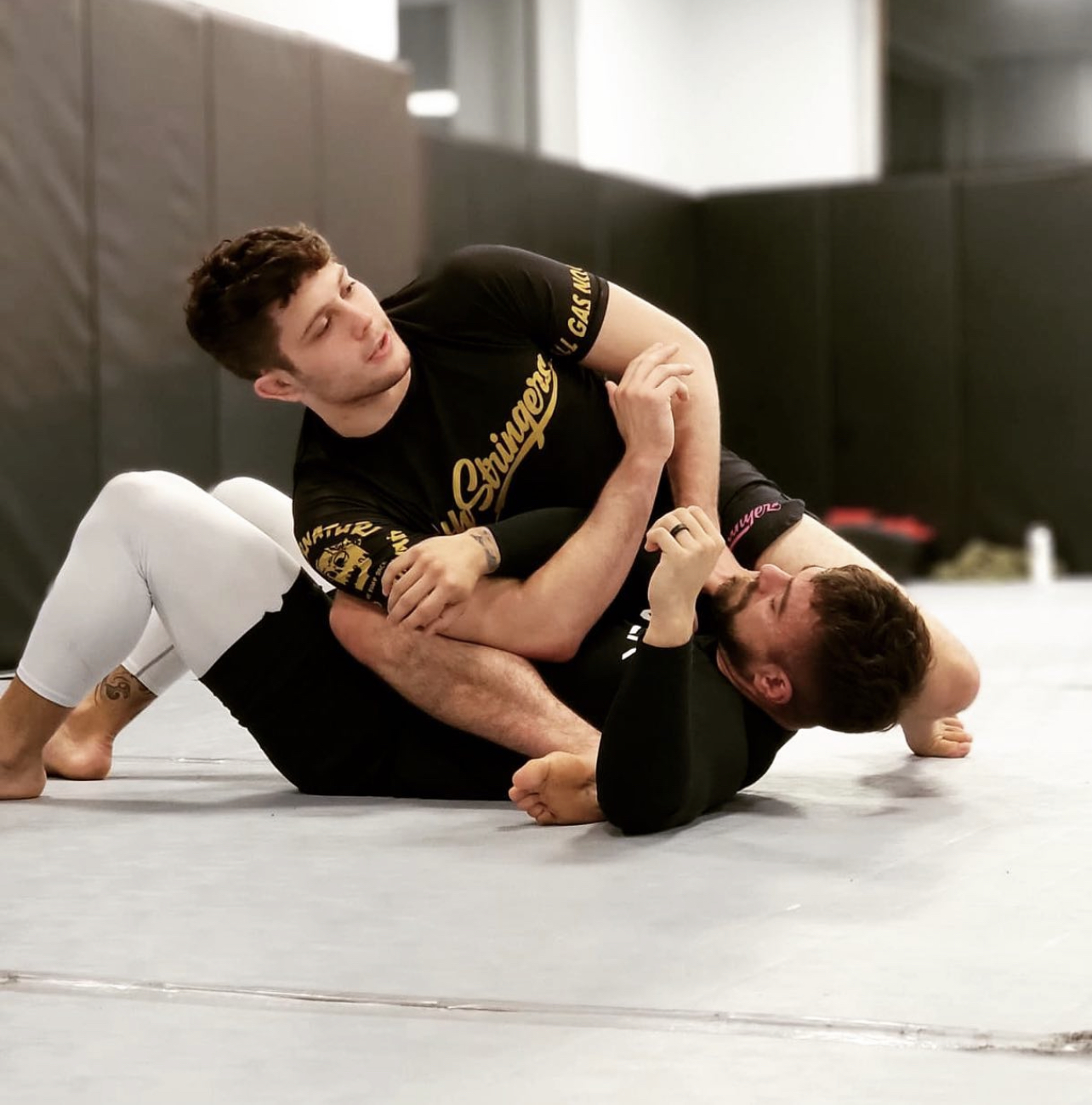 sean yadimarco defeats a jiu-jitsu partner in competition. both men are on the floor of a gym