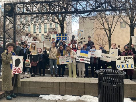 students stand on the plaza holding signs in support of ukraine