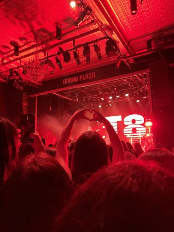 fan holding hands in shape of a heart for tate mcrae with red lighting