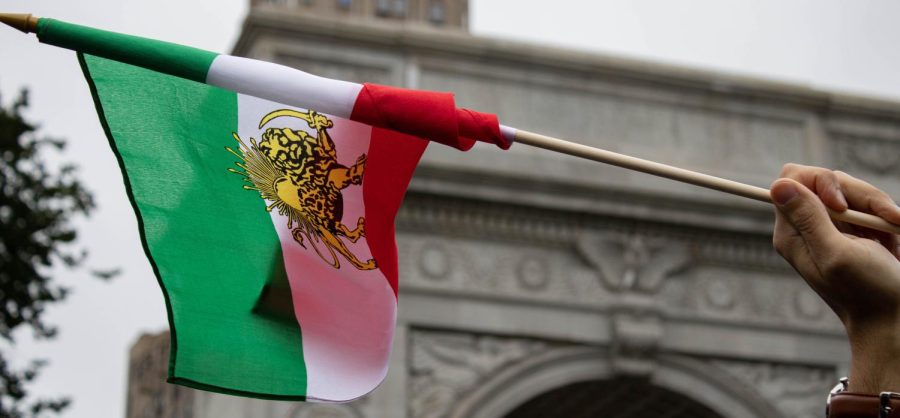 A protester waves the flag of the Imperial State of Iran in the air on Oct. 1 as part of the Coordinated Global Protests Around the World at Washington Square Park.