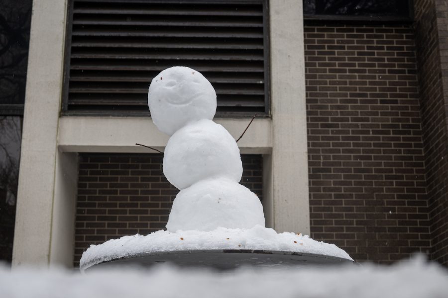 A smiling snowman sits on a table near John Mulcahy Hall. 
