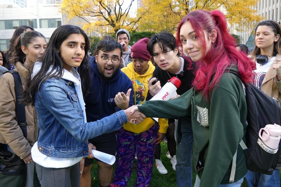 Fordham students gather around Mollin and Chen on Fordham’s Outdoor Plaza to participate in a video.