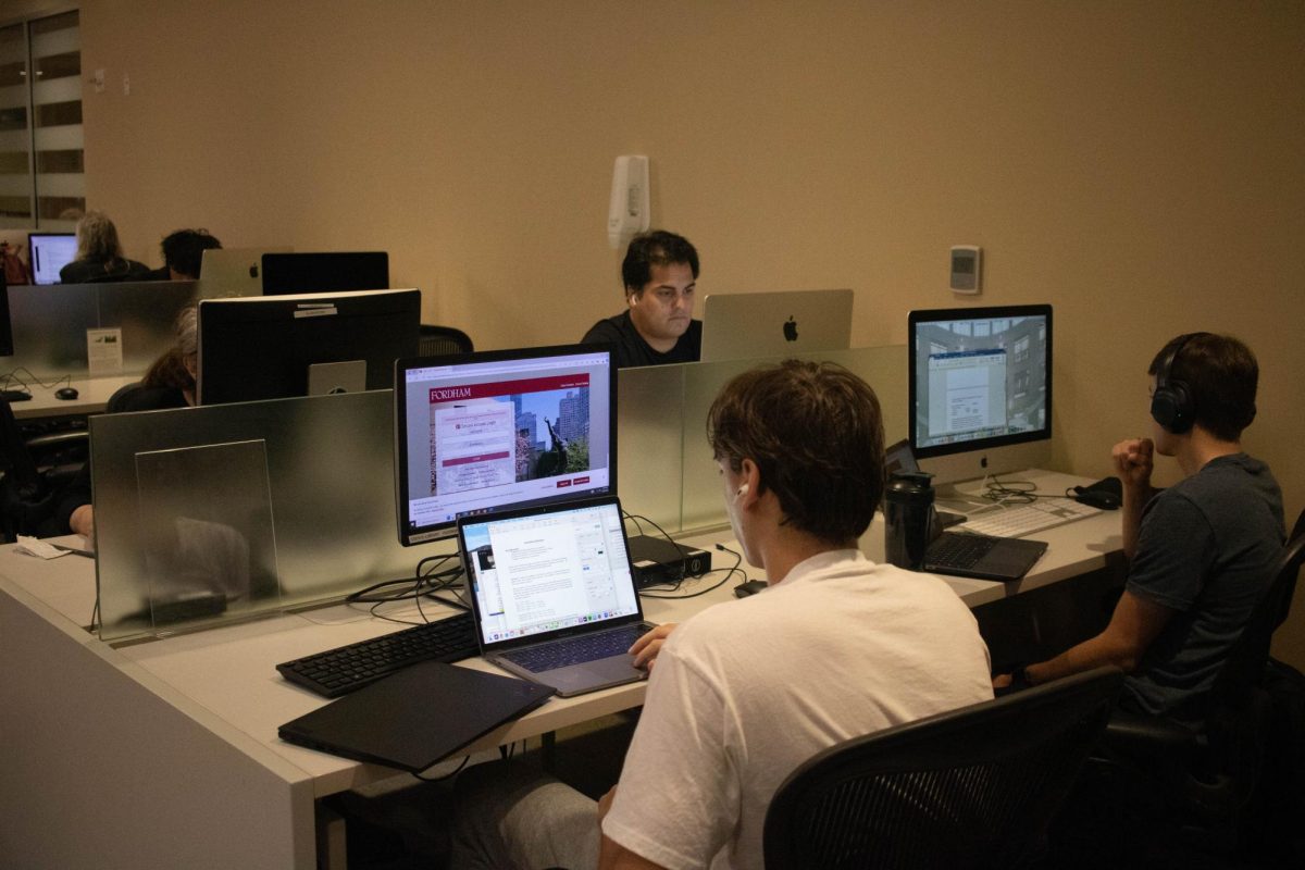 Students at Fordham’s Quinn Library stare at computer screens. 
